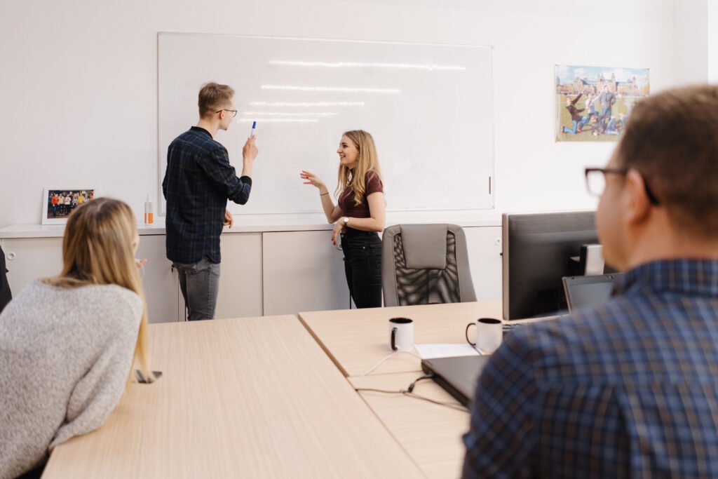 young businessman discussing with colleagues over whiteboard at office